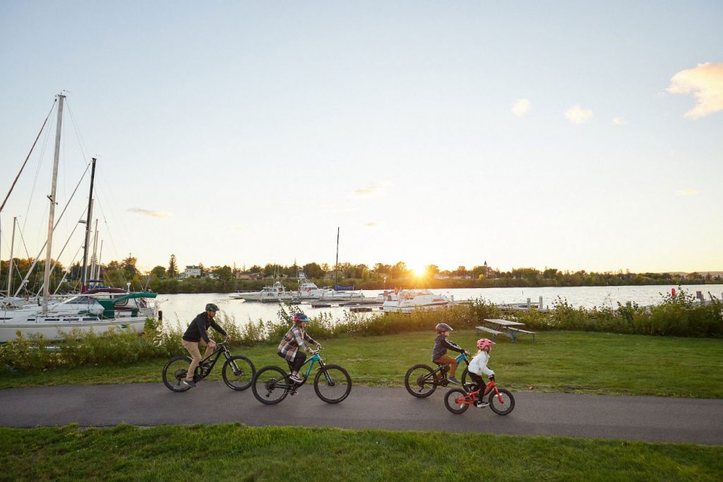 A family of four is biking along a marina.