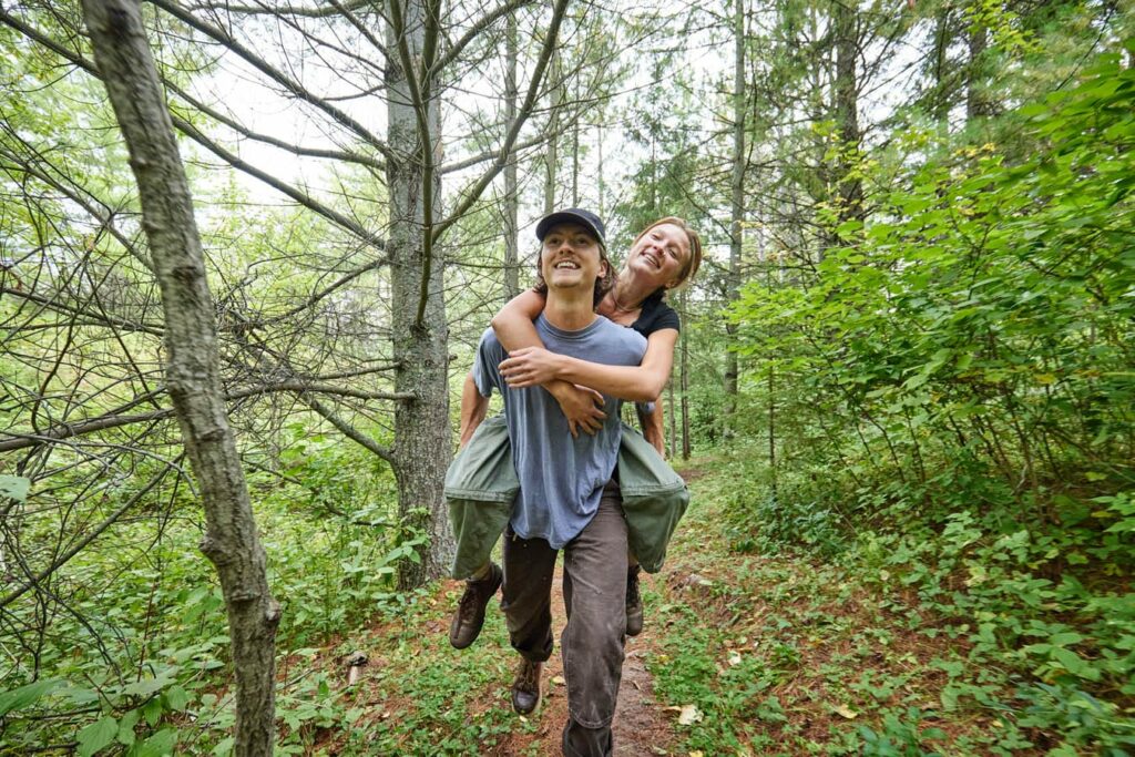 A young, happy couple on a hike. She is riding piggy back on his back.