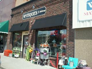 Exterior photo of Antiques on Belknap. There are lots of old and colorful items leaning up on the side of the building.