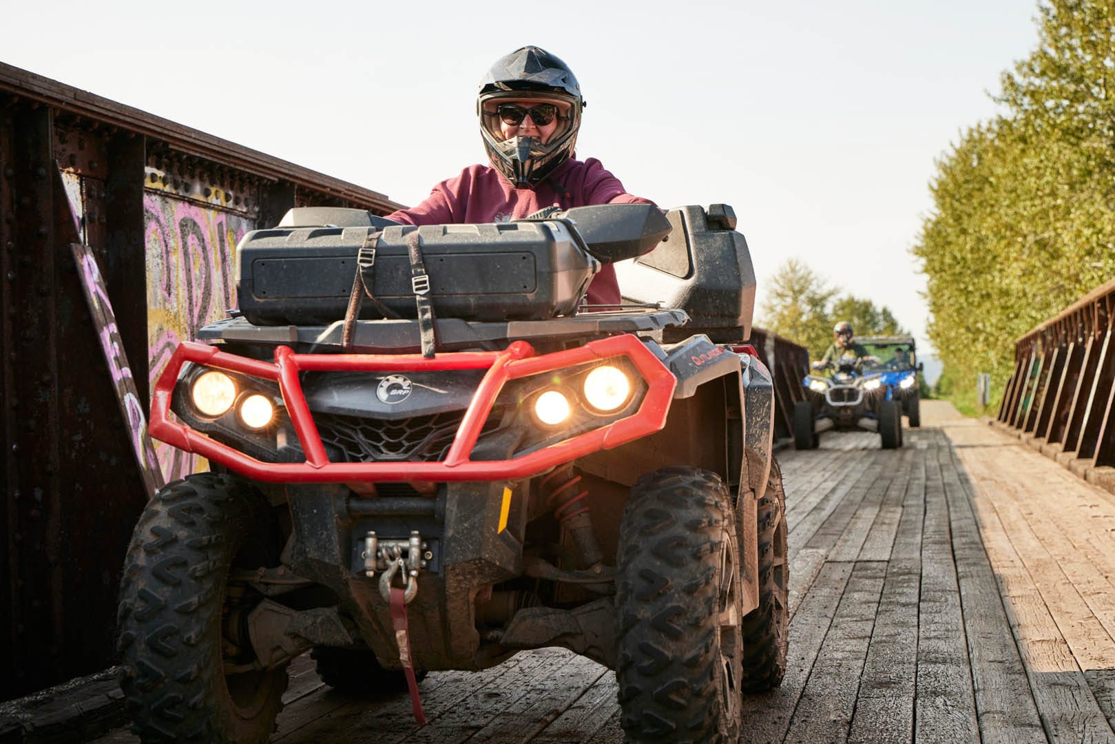 A woman smiles at the camera as she passes in her red UTV.