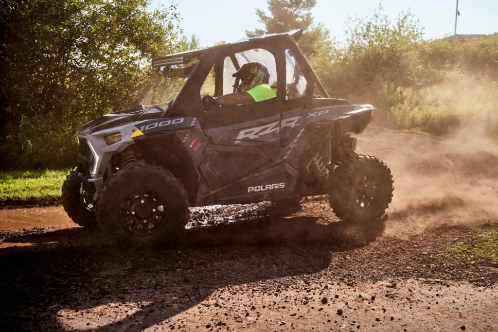 A man is driving an ATV through the mud.