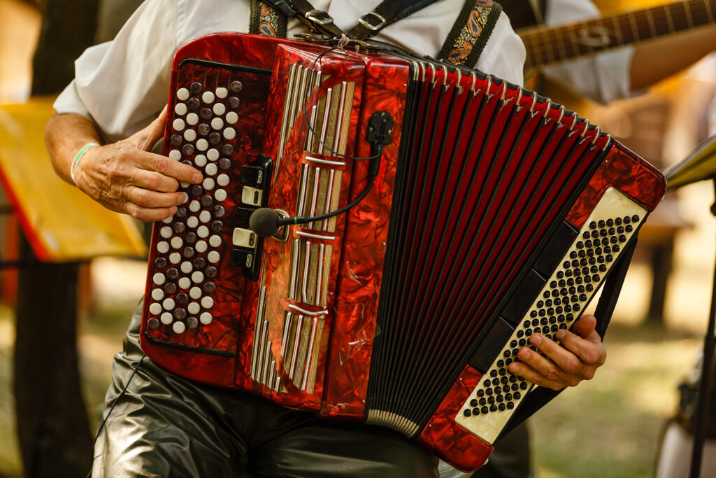A closeup of a man holding a red accordian.