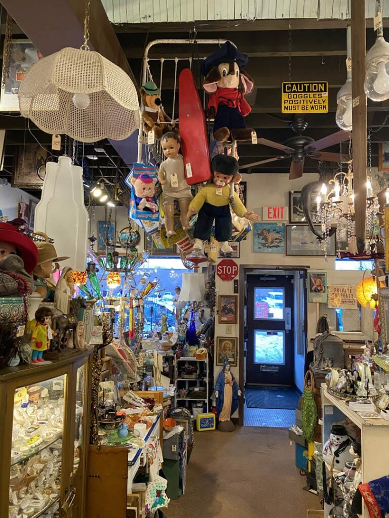 Antique store with antiques at every corner. There are toys and lights hanging from the ceiling.