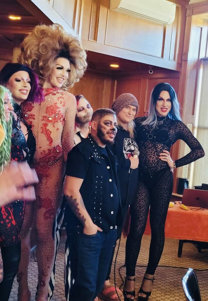 A beautiful bunch of drag queens standing close to each other, smiling and getting their picture taken.