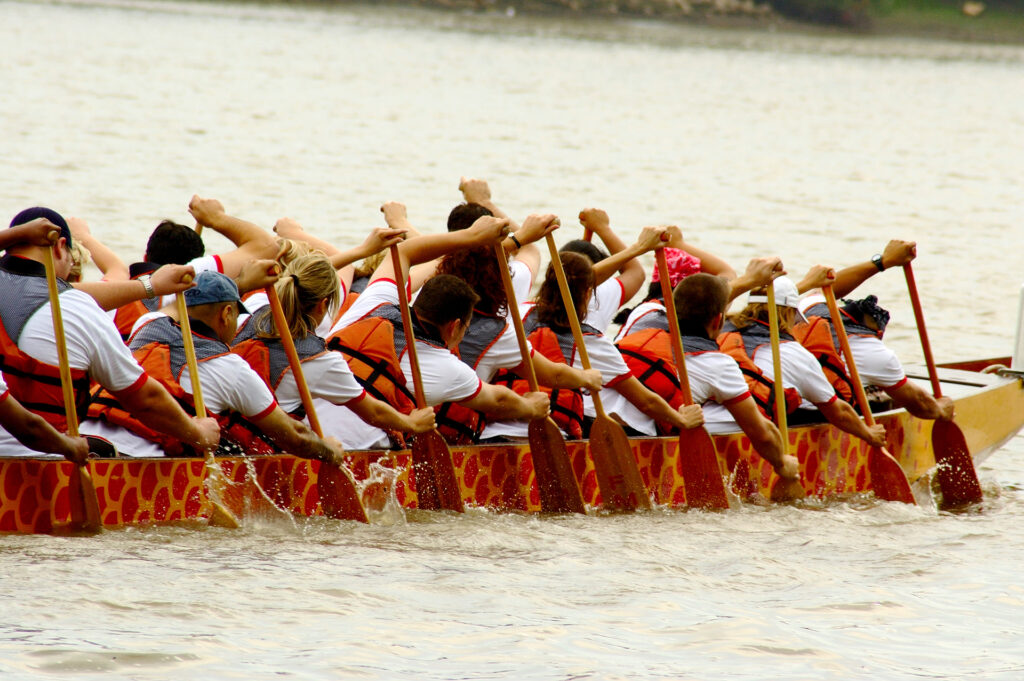 A large group of people paddling in a dragon boat.