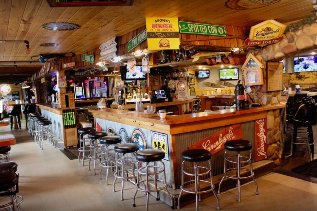 The interior of Gronks Bar in Superior. There's beer signs on the walls and the bar is made of wood and steel and there are stools all along the bar.