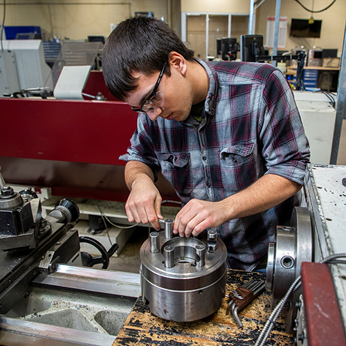 A male student is working on a hands-on project on campus.