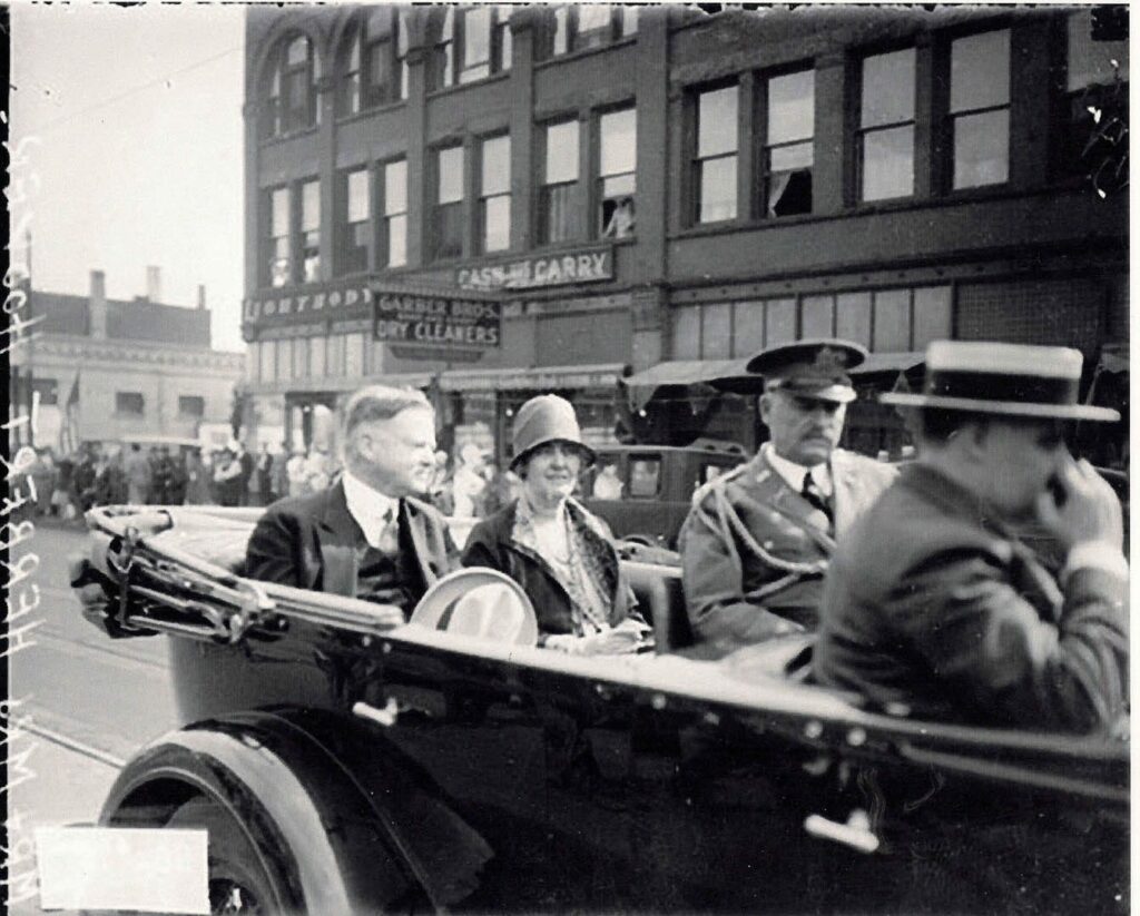 An old black and white photo of Mr and Mrs Herbert Hoover in a model t convertible car on Tower Avenue in Superior