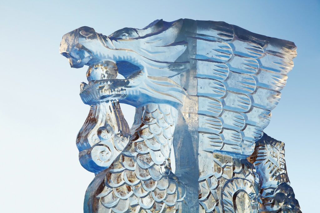 A dragon-face ice sculpture against a blue sky