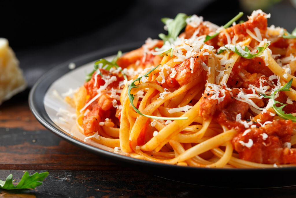 A plate of spaghetti noodles covered in red tomato sauce and white cheese.