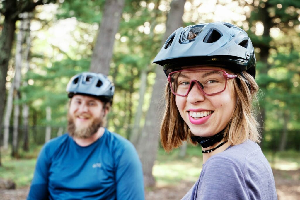 Two helmeted mountain bikers smiling at the camera.