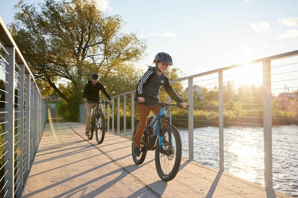 A father and son riding a bike trail with the sun shining.
