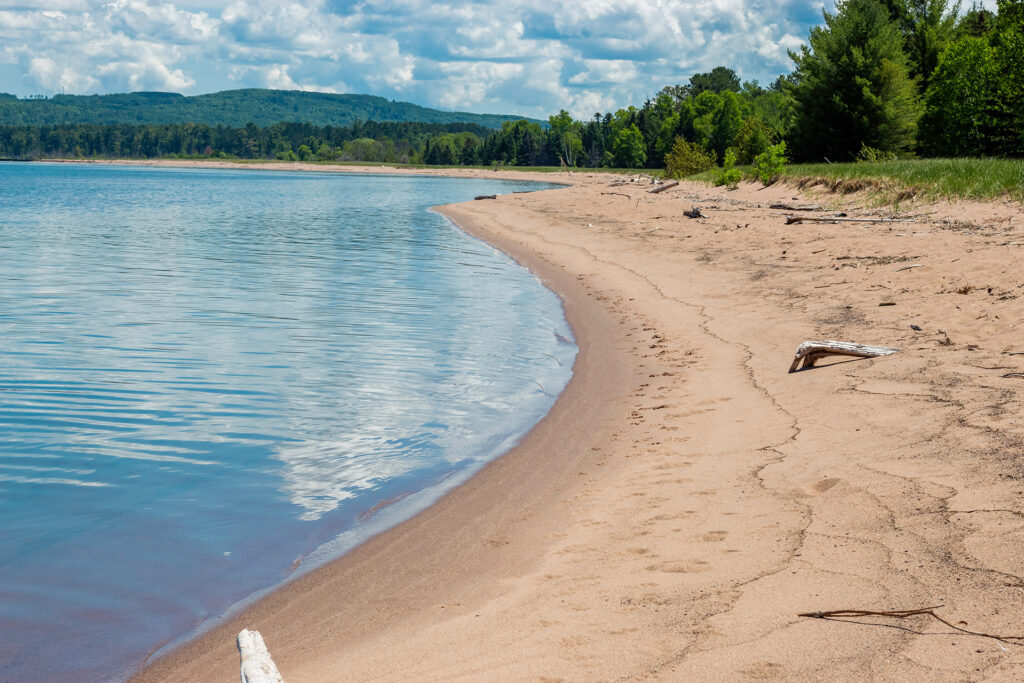 A curving, sandy beach along Lake Superior's blue water in Wisconsin.
