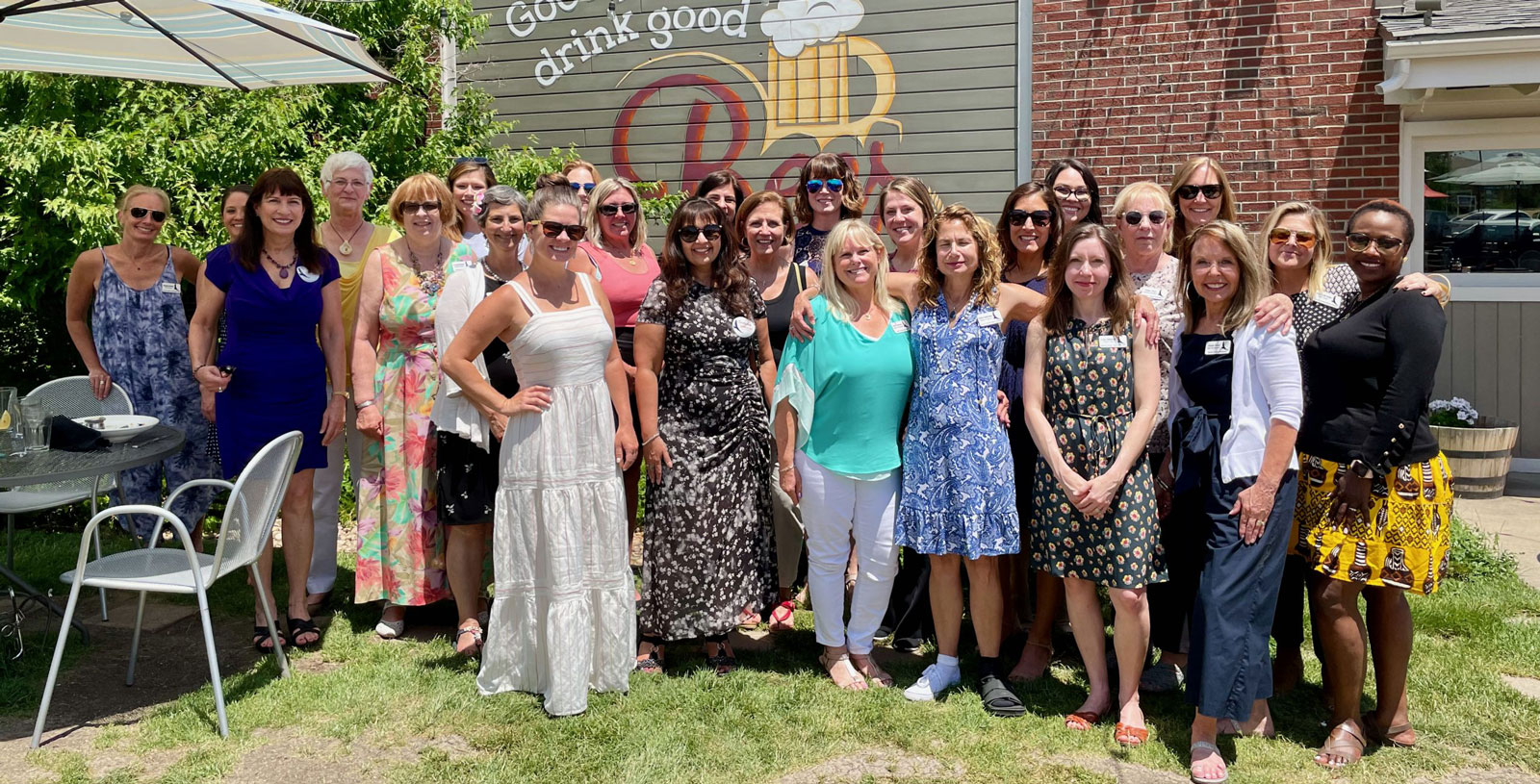 25 women in a group photo, smiling and looking happy on a beautiful sunny day.