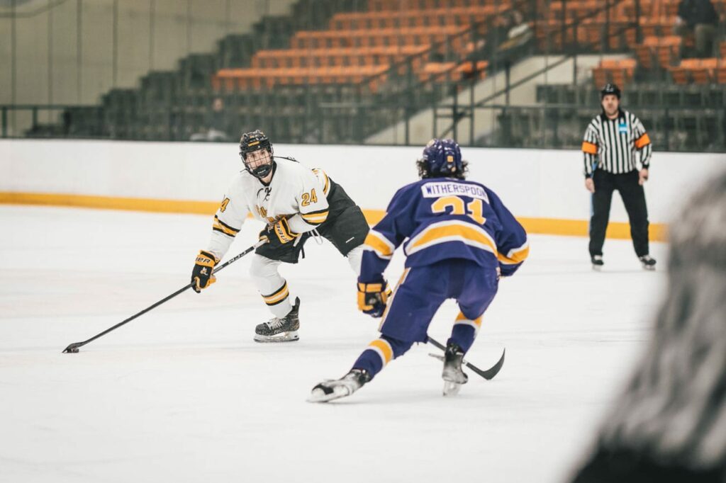 Two guys going after puck with the ref watching.