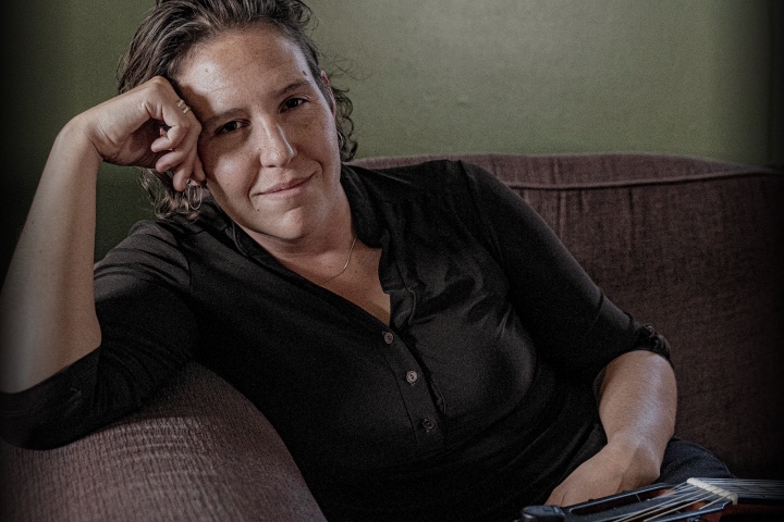 A woman smiling at the camera while sitting on a couch.