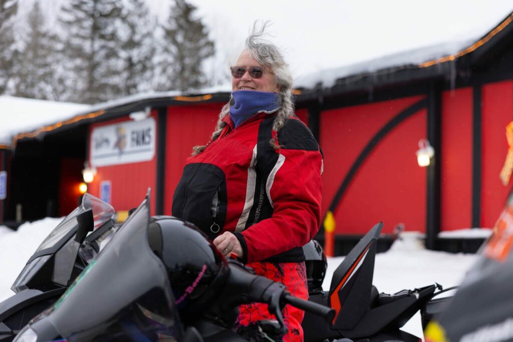 Woman smiling on a snowmobile while taking a break