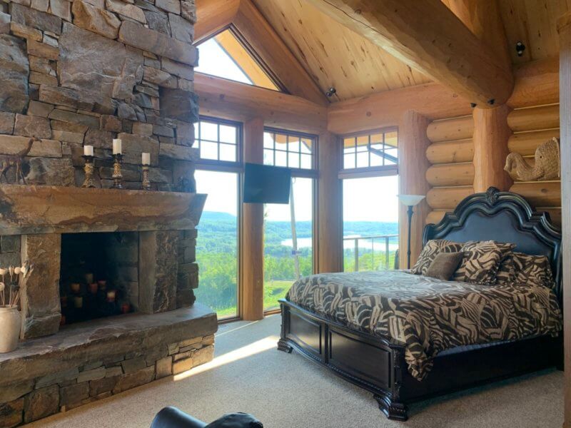 The inside of a suite at Mont du Lac with a big stone fireplace, vaulted ceilings, and a large bed.
