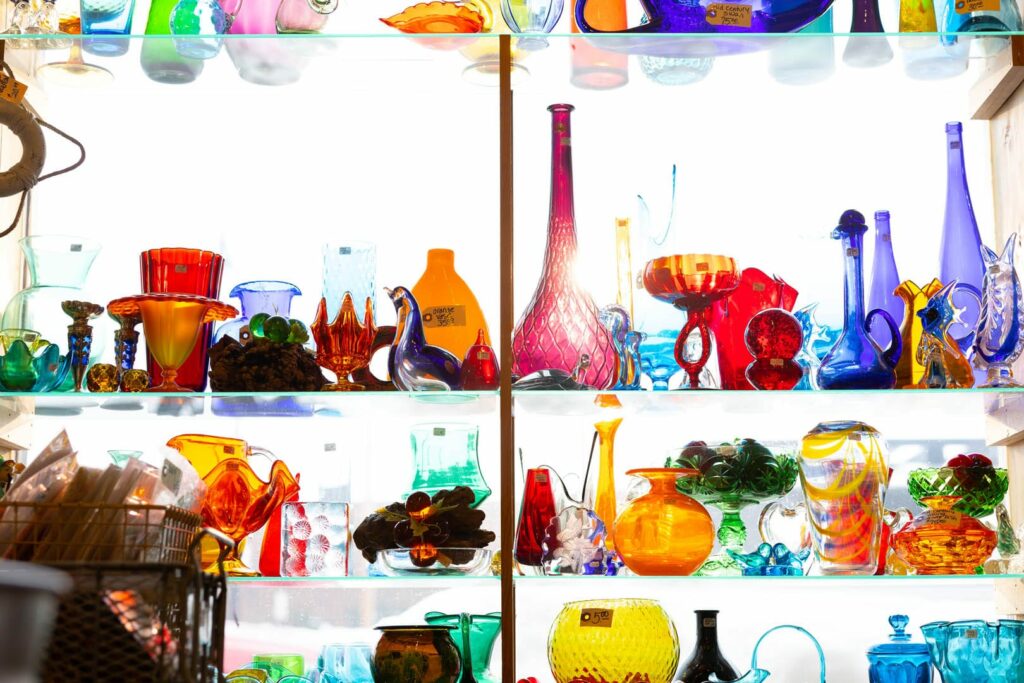 A collection of colorful glasswares on a shelf.