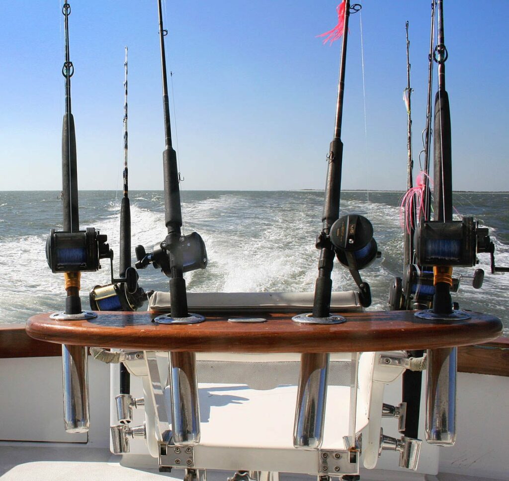 Fishing rods in holders as the line is dragging out behind a boat.