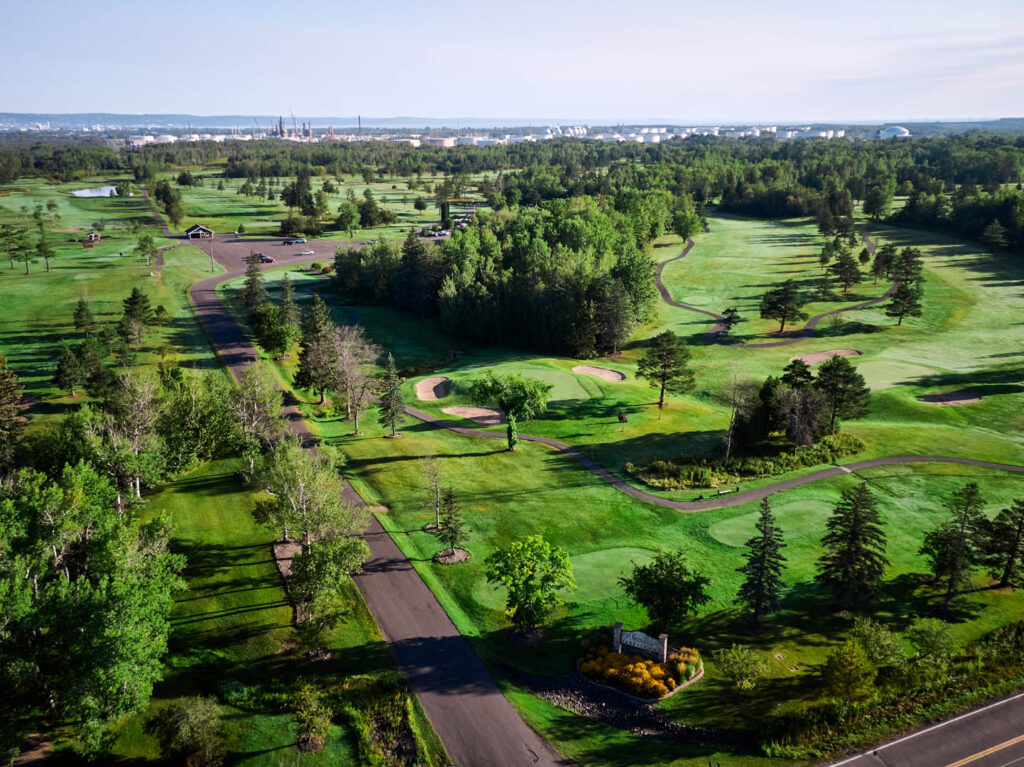 A drone photo of the Nemadji Golf course from above. The course is very hilly, green and has lots of trees along the fairways.