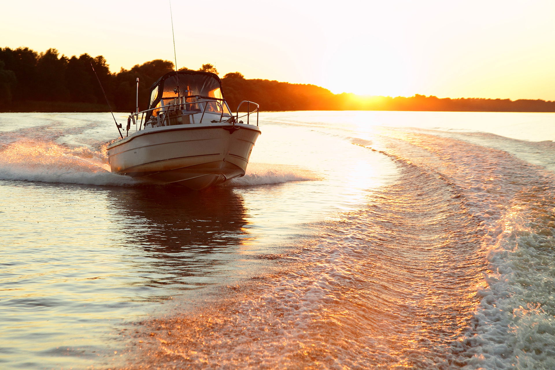 Fishing boat riding down the river at sunset.
