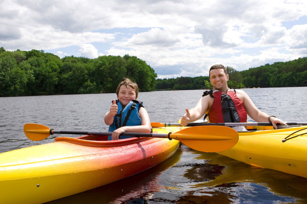 Dad and son riding yellow kayaks down a river.