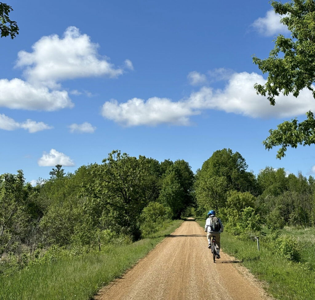 Person biking down the Gandy Dancer Trail.