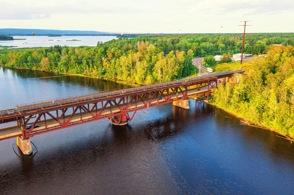 A wind turbine stands in the ocean at sunset, surrounded by calm water with soft pink, blue, and purple tones in the sky—reminiscent of summer activities in Superior Wisconsin along tranquil lakeshores.