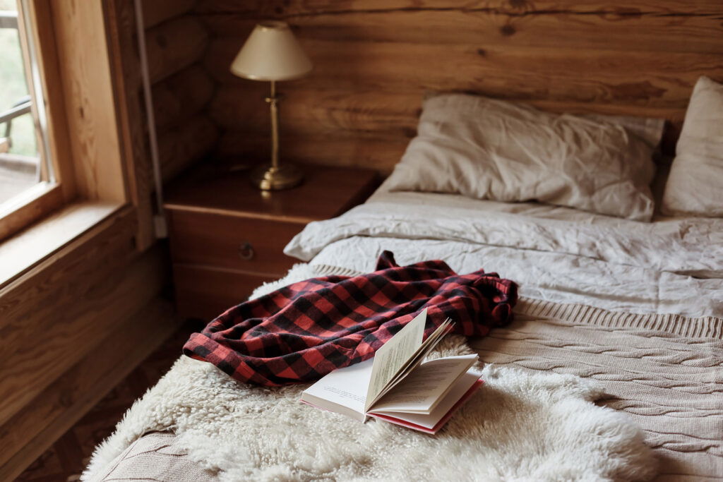 A book and a blanket on a bed set the scene for relaxing after enjoying summer activities in Superior, Wisconsin.