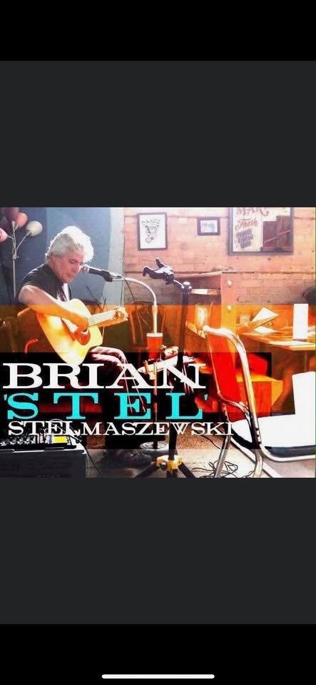 A man with gray hair plays an acoustic guitar and sings into a microphone at a cafe. There are orange chairs, art on the walls, and large text in the foreground that reads, "BRIAN STELMASZEWSKI.