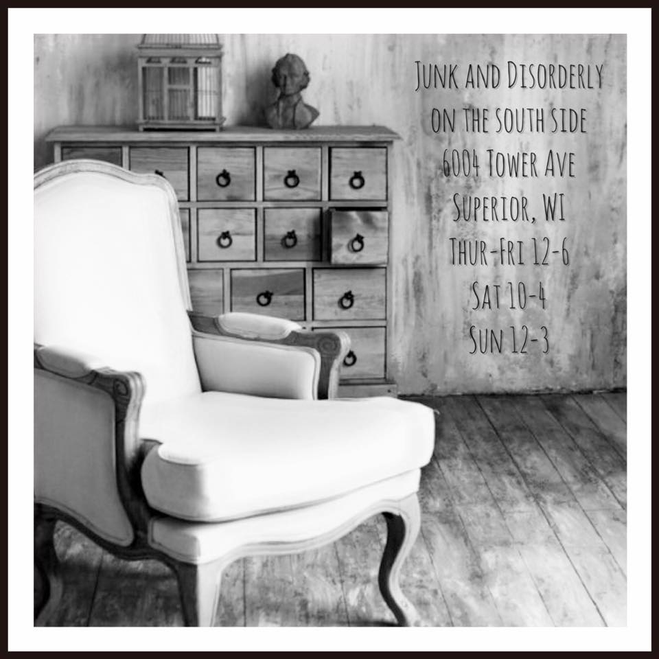 Black and white photo of a vintage armchair in front of a rustic wooden dresser. Text provides store info: Junk and Disorderly, 6004 Tower Ave, Superior, WI; open Thurs-Fri 12-6, Sat 10-4, Sun 12-3.
