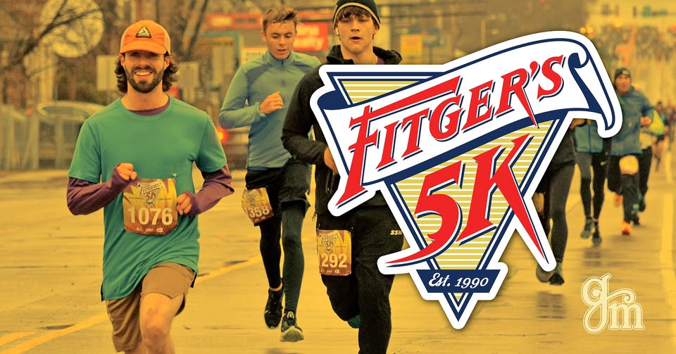 Runners participating in the Fitger’s 5K race, wearing race bibs and athletic gear, with a large Fitger’s 5K logo in the foreground and other runners visible in the background.