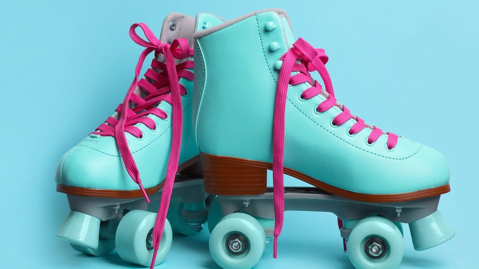 A pair of retro-style teal roller skates with pink laces and brown soles against a light blue background.