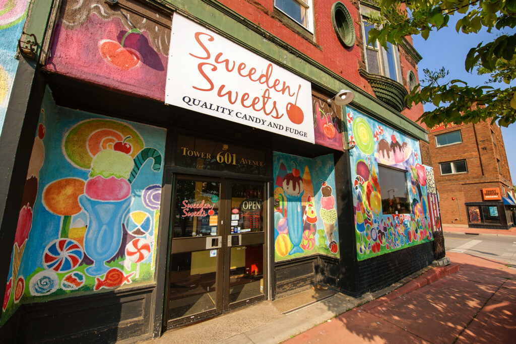 Colorful storefront of Sweeten Sweets candy and fudge shop with vibrant murals of ice cream, lollipops, and other sweets—an irresistible stop for Wisconsin family vacations; sign above the door reads "Sweeten Sweets.