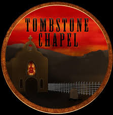 A dark, round logo with a chapel silhouette and a glowing red window, set against a dramatic red-orange sunset. The words "TOMBSTONE CHAPEL" are written above the chapel in bold black letters.