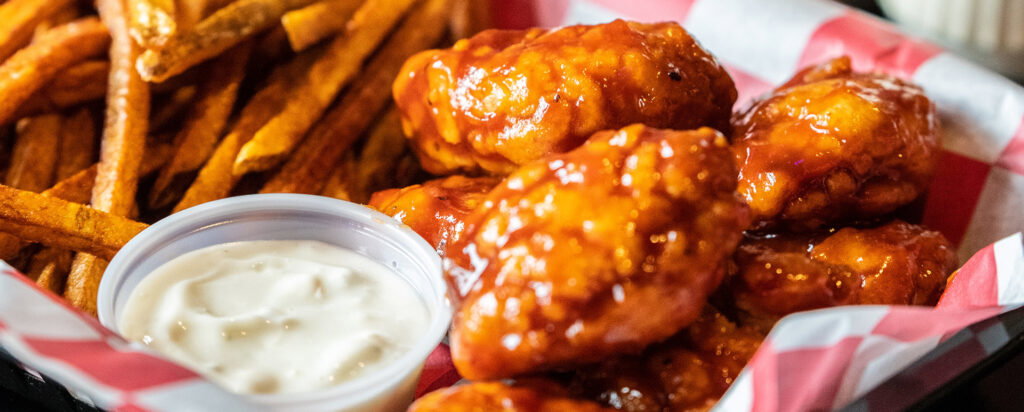 A distorted, abstract image featuring vibrant orange and red hues with hints of metallic silver and black, creating a dynamic, textured visual pattern with blurred, layered shapes.