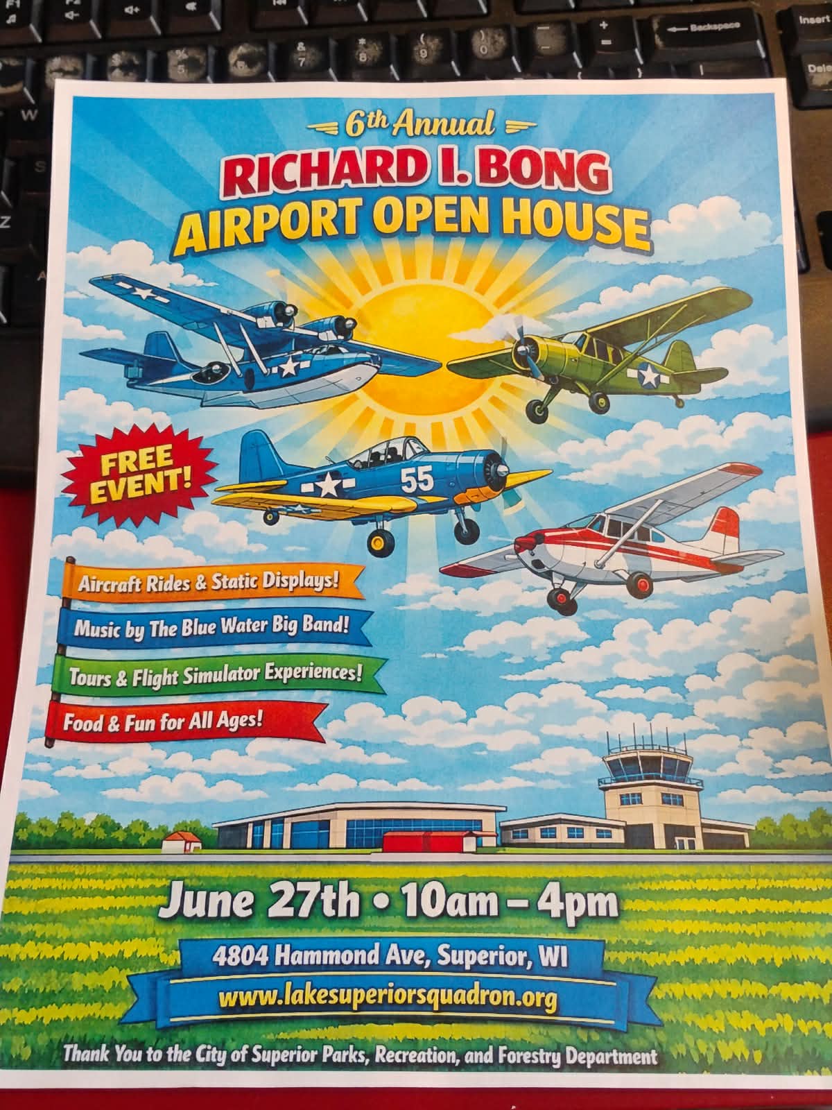Colorful event poster for the "6th Annual Richard I. Bong Airport Open House" featuring vintage planes, event details, and a cartoon airport. Highlights include free entry, aircraft displays, tours, and activities for all ages.