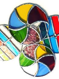 Colorful stained glass pieces with various geometric shapes and vibrant hues, including blue, red, yellow, green, and pink, arranged in a decorative overlapping pattern.