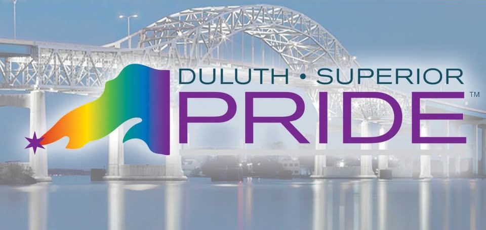 A rainbow flag and star graphic next to the words “Duluth Superior Pride” appear over a photo of a large arched bridge above calm water, with a misty background.