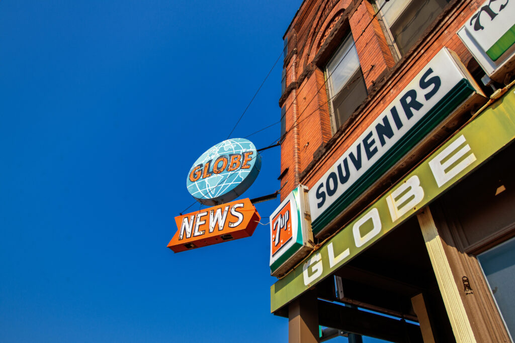 A building with colorful signs reads “GLOBE NEWS,” “SOUVENIRS,” and “GLOBE” against a clear blue sky—an inviting stop for holiday shopping in Superior, Wisconsin. The “GLOBE” sign features a globe graphic above the word “NEWS.”.